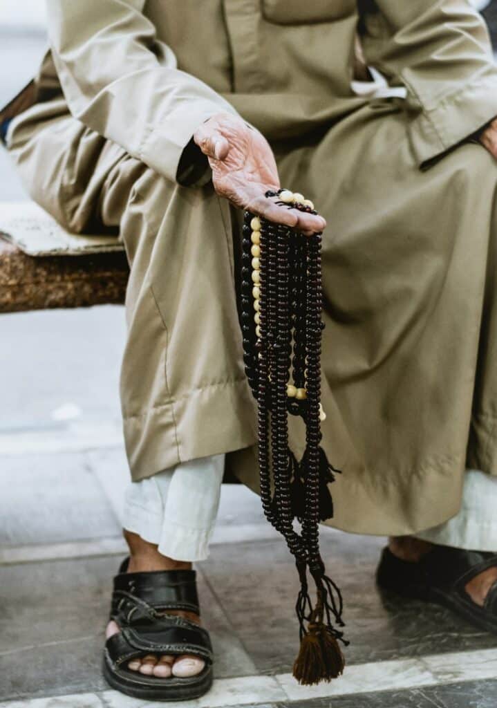 old man holding a bead composed of eagle eye stones