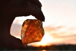 honey calcite held by a hand against sunlight